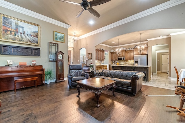 living room featuring sink, ceiling fan with notable chandelier, crown molding, and dark wood-type flooring