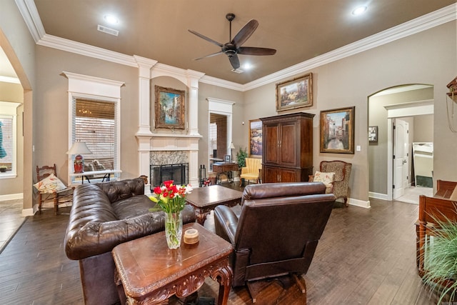 living room featuring a fireplace, dark hardwood / wood-style flooring, ceiling fan, and crown molding