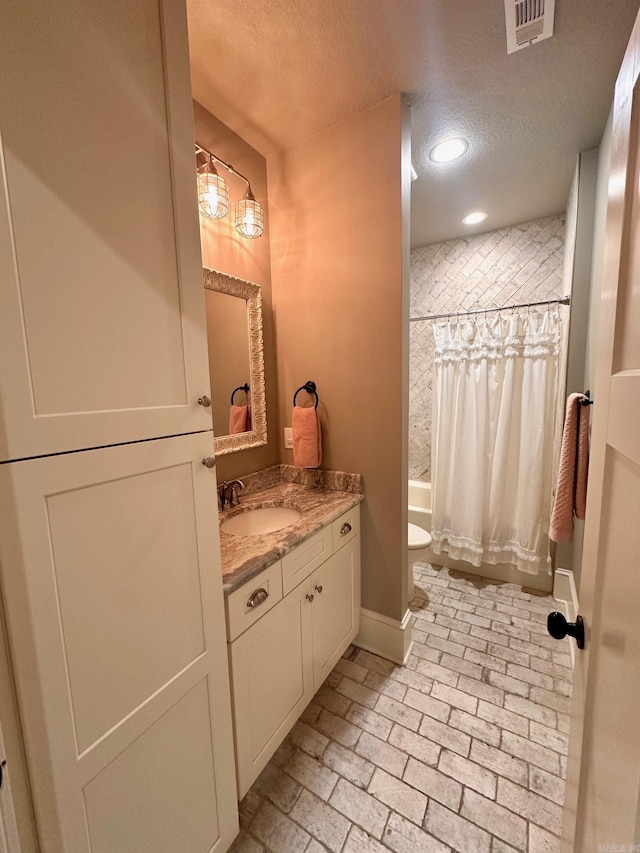 full bathroom with toilet, a textured ceiling, shower / tub combo with curtain, and vanity