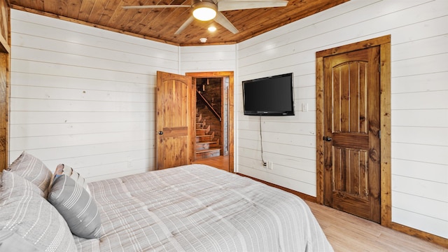 bedroom with light hardwood / wood-style floors, ceiling fan, wooden walls, and wood ceiling