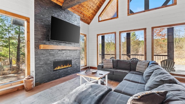 living room with a stone fireplace, beamed ceiling, high vaulted ceiling, wood-type flooring, and wood ceiling