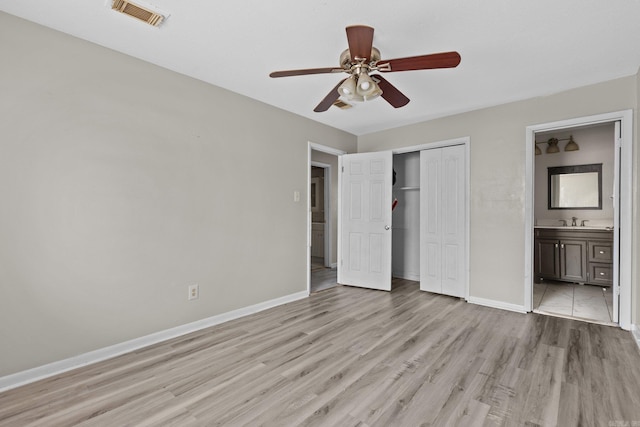 unfurnished bedroom with ensuite bathroom, ceiling fan, sink, light hardwood / wood-style flooring, and a closet