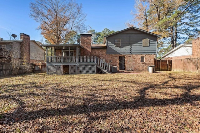 back of property with a sunroom, a wooden deck, and a lawn