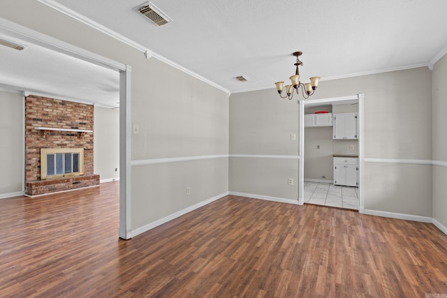 unfurnished dining area featuring dark wood-type flooring, a notable chandelier, a textured ceiling, a fireplace, and ornamental molding