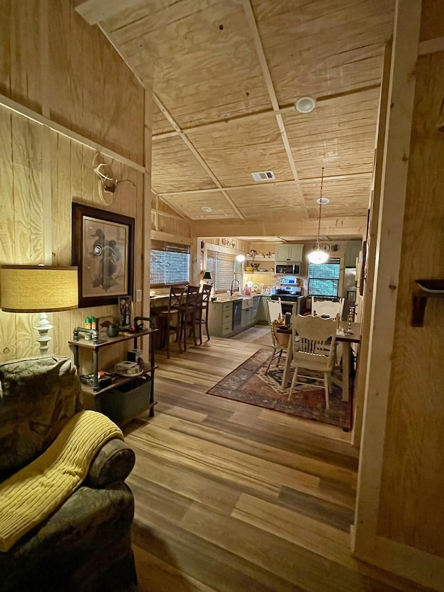 dining room with wood ceiling, sink, hardwood / wood-style flooring, lofted ceiling, and wood walls