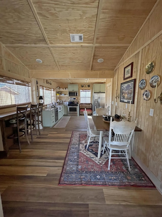 dining space with dark hardwood / wood-style floors, wooden ceiling, and wood walls