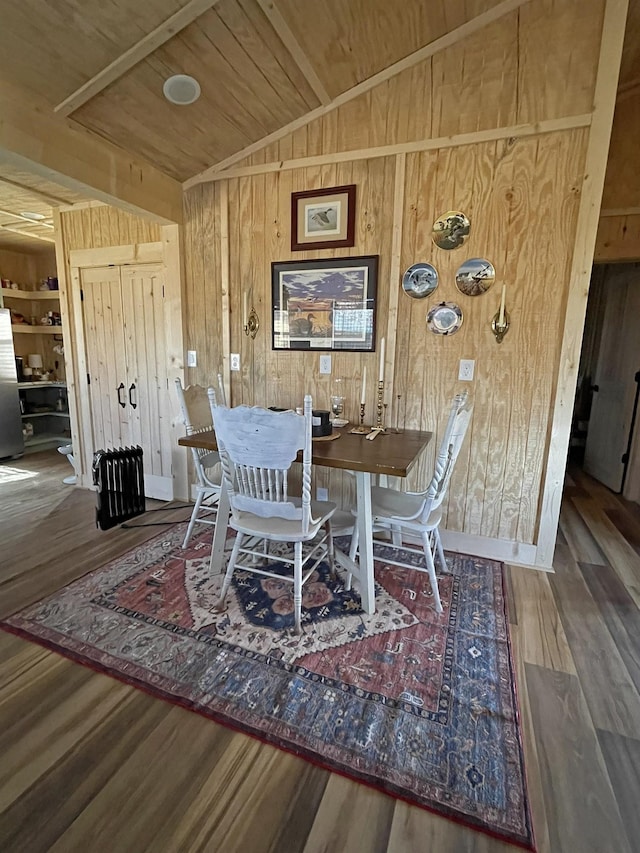 dining room featuring wood walls, wood-type flooring, wooden ceiling, and vaulted ceiling