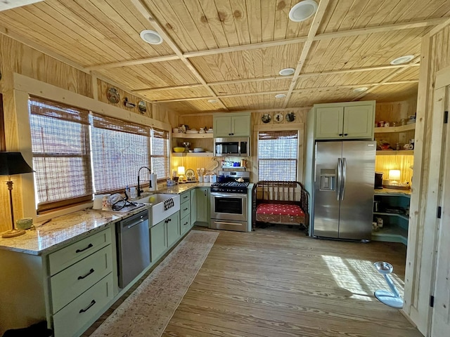 kitchen with light stone counters, stainless steel appliances, sink, light hardwood / wood-style flooring, and green cabinets