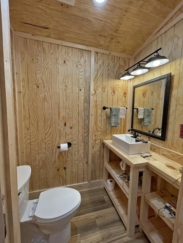 bathroom featuring sink, wooden ceiling, wood walls, hardwood / wood-style floors, and toilet