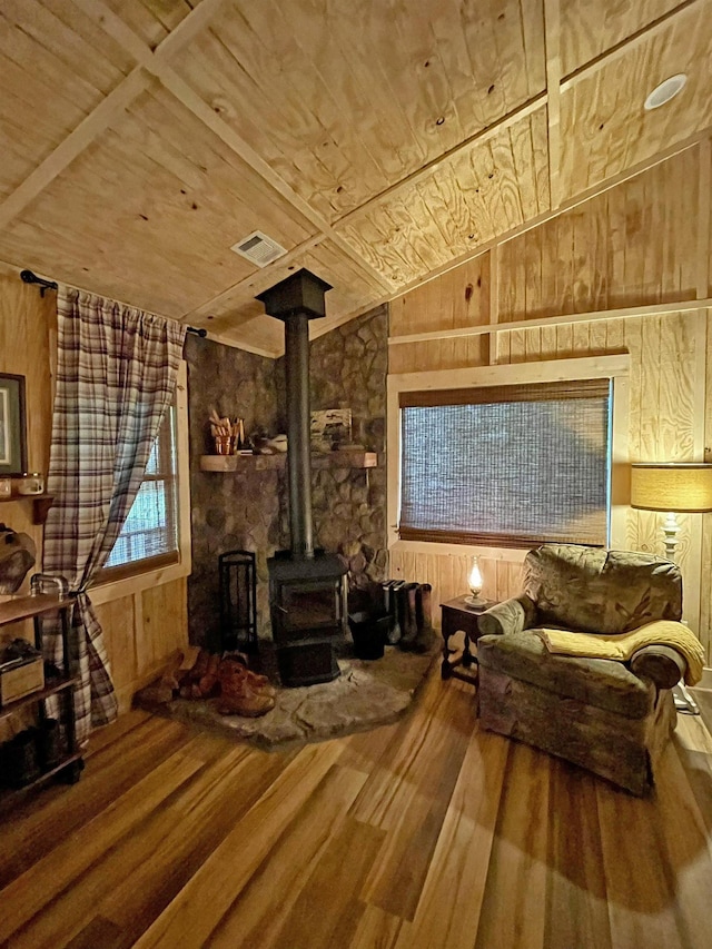 interior space with a wood stove, wood walls, lofted ceiling, wood ceiling, and hardwood / wood-style flooring