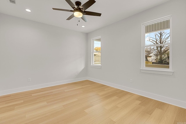 spare room with light wood-type flooring, a wealth of natural light, and ceiling fan