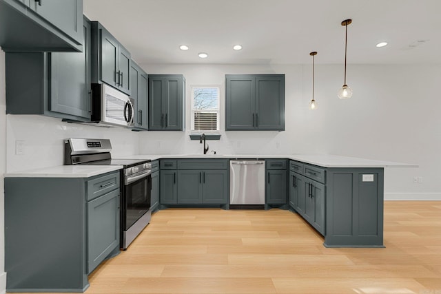 kitchen with kitchen peninsula, appliances with stainless steel finishes, sink, pendant lighting, and gray cabinets