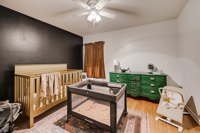 bedroom featuring ceiling fan, a crib, and light wood-type flooring