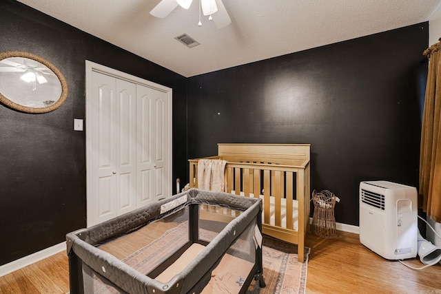 bedroom with ceiling fan, a closet, wood-type flooring, and a textured ceiling