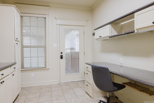 unfurnished office featuring crown molding, light tile patterned flooring, and built in desk