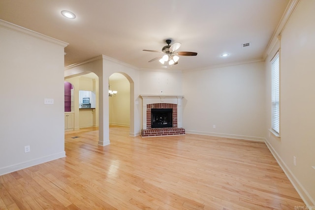 unfurnished living room featuring ceiling fan, light hardwood / wood-style floors, ornamental molding, and a brick fireplace