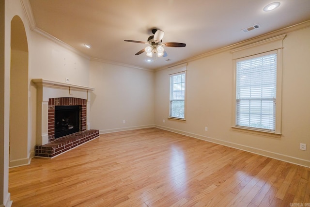 unfurnished living room featuring ceiling fan, light hardwood / wood-style floors, crown molding, and a brick fireplace