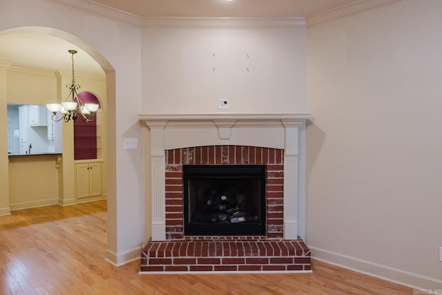 details with a brick fireplace, ornamental molding, wood-type flooring, and an inviting chandelier