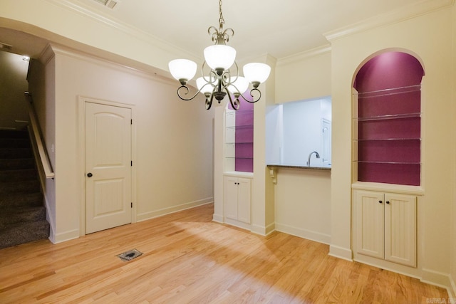 unfurnished dining area with light wood-type flooring, an inviting chandelier, and crown molding