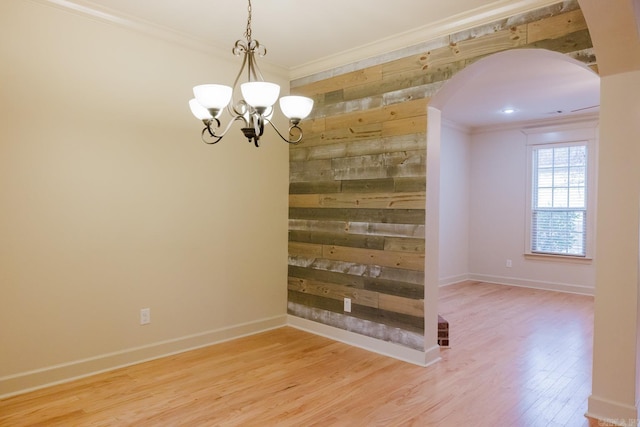 unfurnished dining area with a chandelier, wood walls, ornamental molding, and hardwood / wood-style flooring