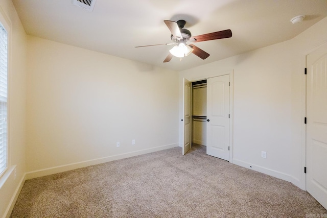 unfurnished bedroom featuring ceiling fan, a closet, and light colored carpet