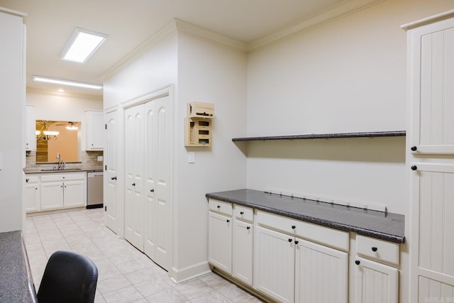 kitchen with sink, dishwasher, light tile patterned floors, white cabinets, and ornamental molding