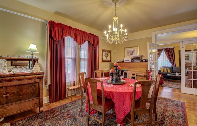 dining area with light hardwood / wood-style floors and an inviting chandelier