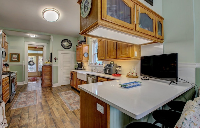 kitchen with kitchen peninsula, a breakfast bar, stainless steel appliances, dark wood-type flooring, and sink