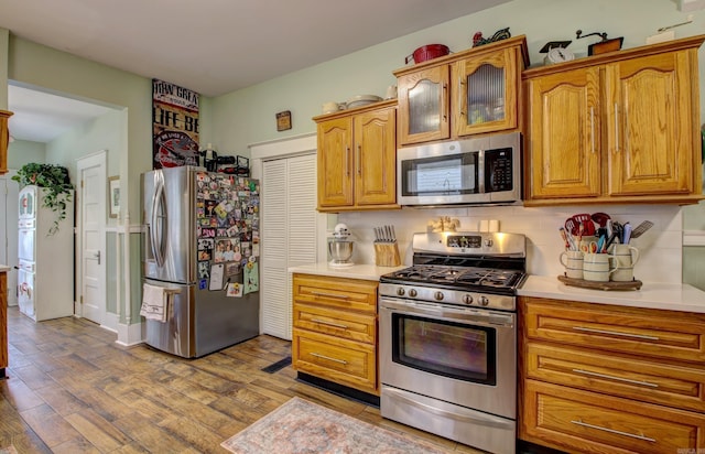 kitchen featuring light wood-type flooring, backsplash, and appliances with stainless steel finishes