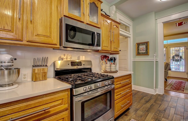 kitchen with decorative backsplash, appliances with stainless steel finishes, and dark wood-type flooring