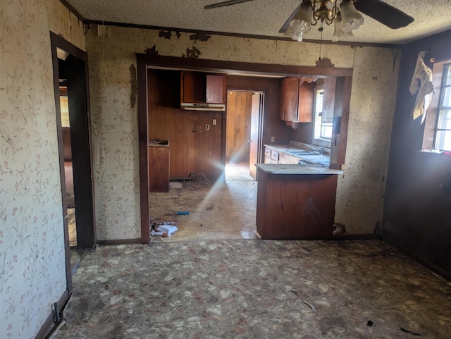 kitchen with ceiling fan, kitchen peninsula, sink, and a textured ceiling