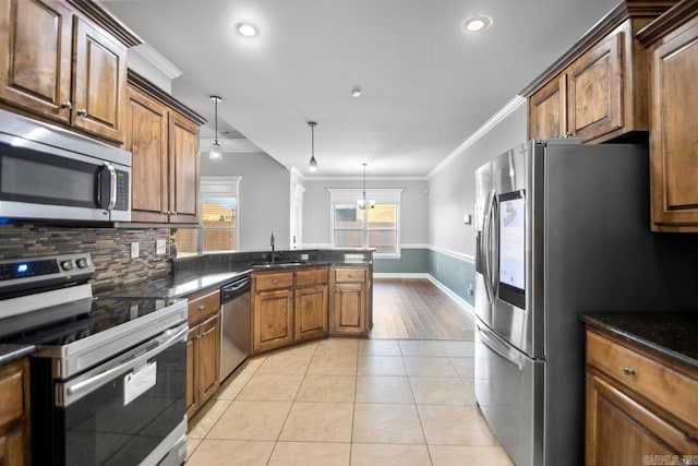 kitchen with sink, appliances with stainless steel finishes, pendant lighting, light tile patterned floors, and ornamental molding