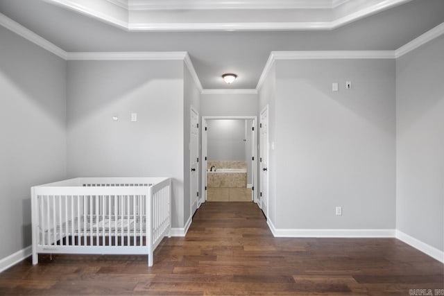 unfurnished bedroom with dark wood-type flooring, a nursery area, and ornamental molding