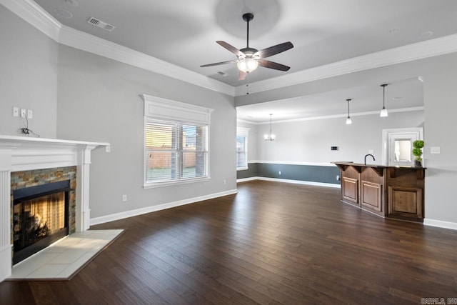 living room with a stone fireplace, crown molding, and dark hardwood / wood-style flooring