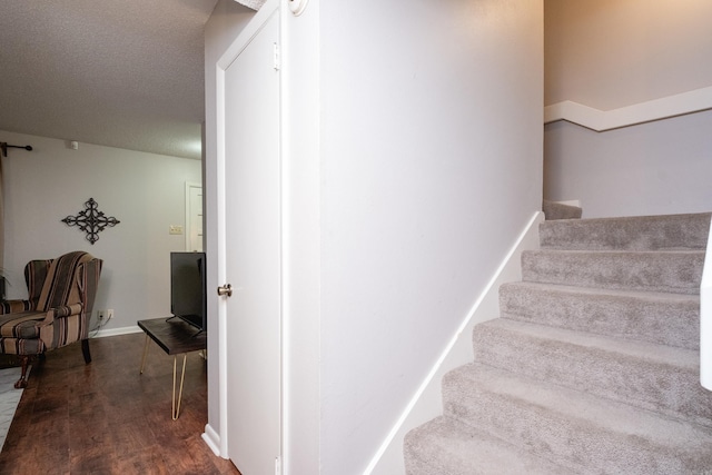 stairs featuring hardwood / wood-style flooring and a textured ceiling