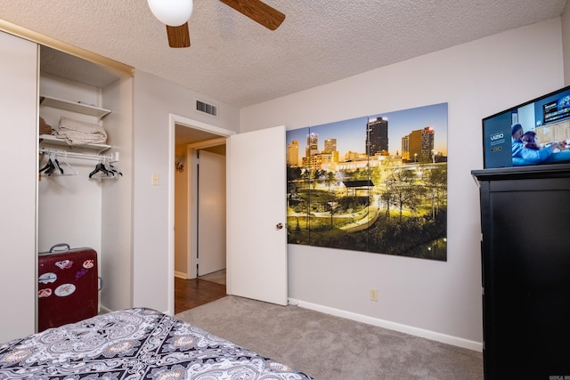 carpeted bedroom featuring ceiling fan, a textured ceiling, and a closet