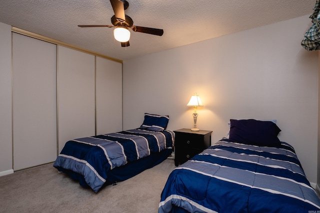 carpeted bedroom featuring ceiling fan, a textured ceiling, and a closet