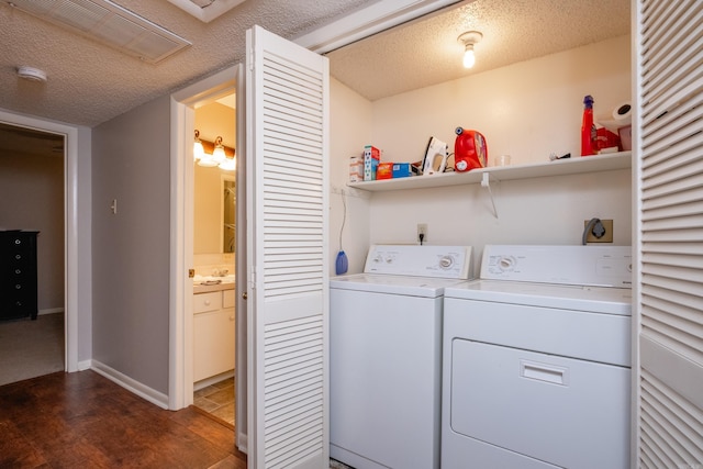 laundry area featuring sink, dark hardwood / wood-style flooring, a textured ceiling, and washing machine and clothes dryer