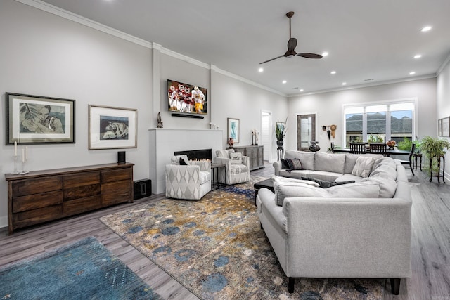 living room featuring hardwood / wood-style floors, ceiling fan, and ornamental molding