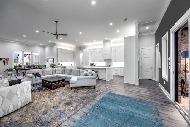 living room featuring ceiling fan, dark wood-type flooring, and ornamental molding