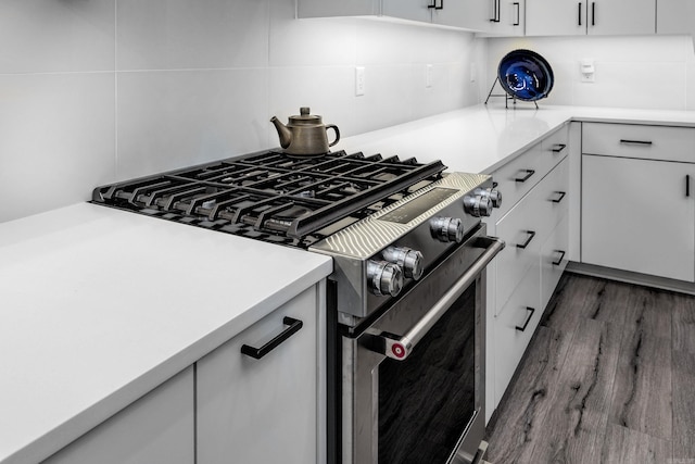 kitchen with backsplash, white cabinetry, stainless steel range, and dark wood-type flooring