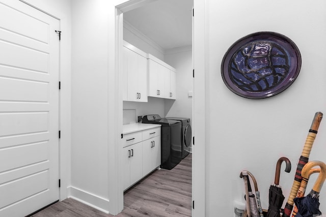 interior space featuring white cabinets, light wood-type flooring, separate washer and dryer, and crown molding