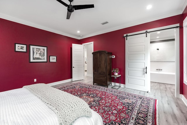 bedroom featuring a barn door, ceiling fan, light hardwood / wood-style floors, and ornamental molding