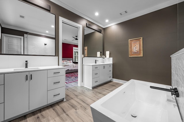 bathroom with ceiling fan, a washtub, wood-type flooring, vanity, and ornamental molding