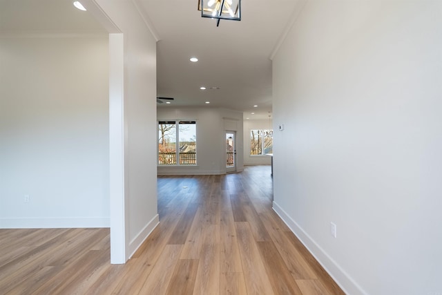 hall featuring crown molding, light hardwood / wood-style floors, and a notable chandelier