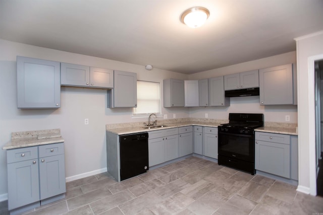 kitchen with sink, light stone counters, gray cabinetry, and black appliances