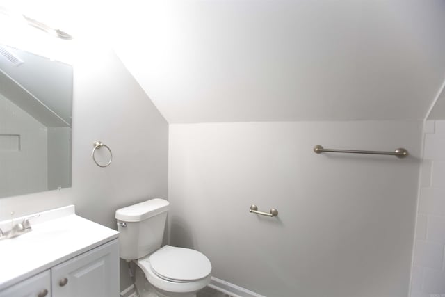 bathroom featuring vanity, lofted ceiling, and toilet