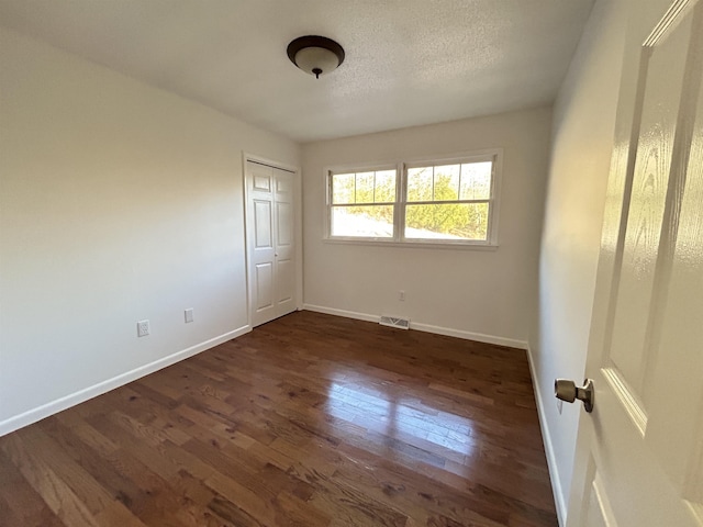 unfurnished bedroom with a closet and dark wood-type flooring