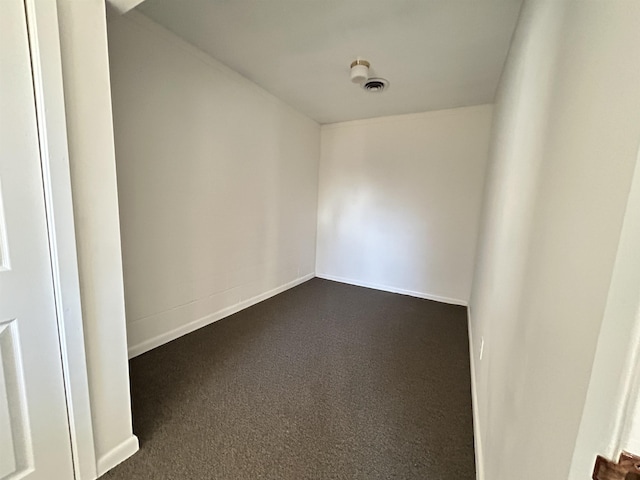 spare room with dark carpet