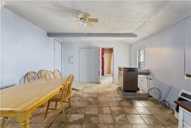 dining space featuring beamed ceiling, heating unit, ceiling fan, and wooden walls